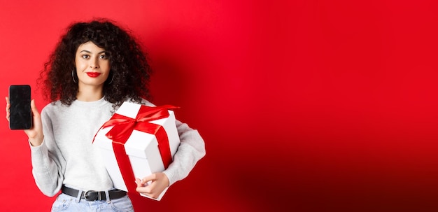portrait of young woman standing against red background