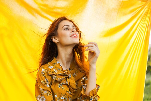 Portrait of young woman standing against red curtain