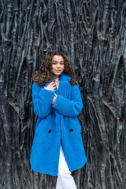 Foto ritratto di una giovane donna in piedi contro il tronco di un albero