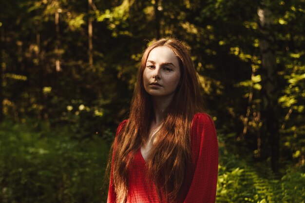 Portrait of young woman standing against trees