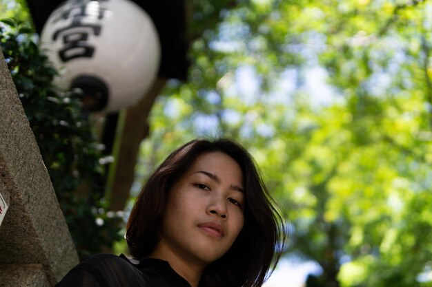 Portrait of young woman standing against trees