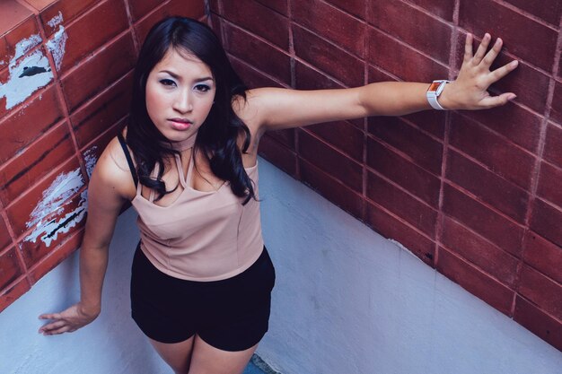 Portrait of young woman standing against wall