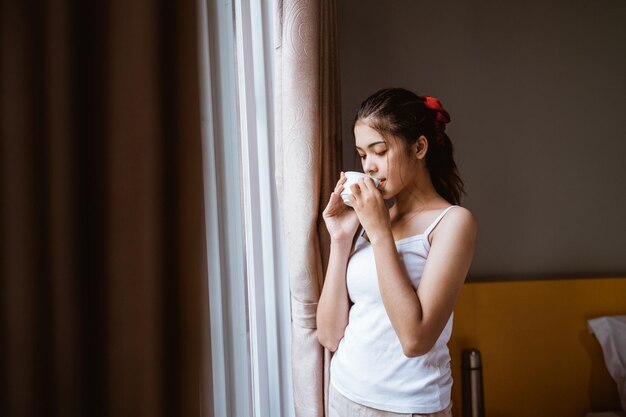 Portrait of young woman standing against wall