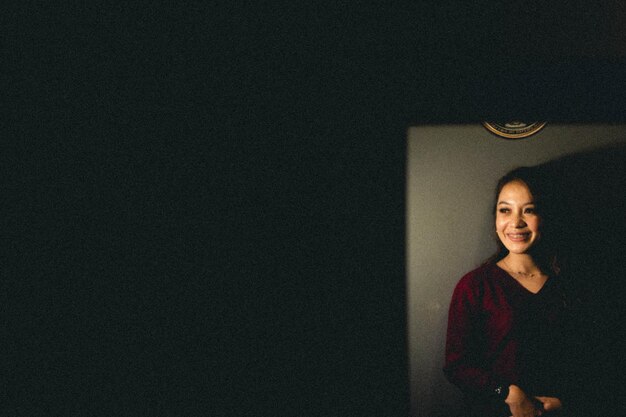 Portrait of young woman standing against wall