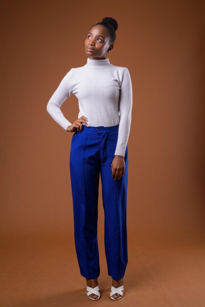 Portrait of young woman standing against wall