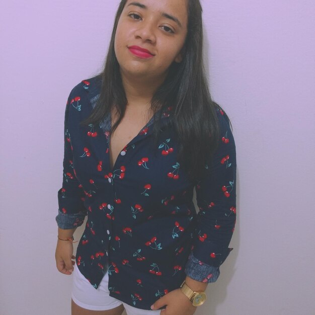 Portrait of young woman standing against wall