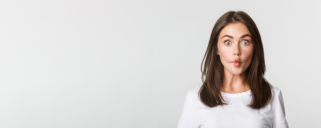 Portrait of young woman standing against white background