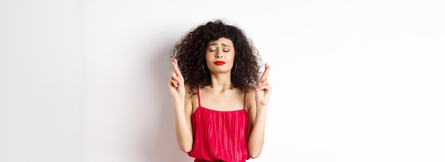 Portrait of young woman standing against white background