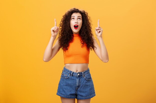 Portrait of young woman standing against yellow background