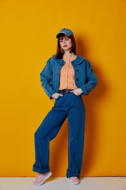 Portrait of young woman standing against yellow background