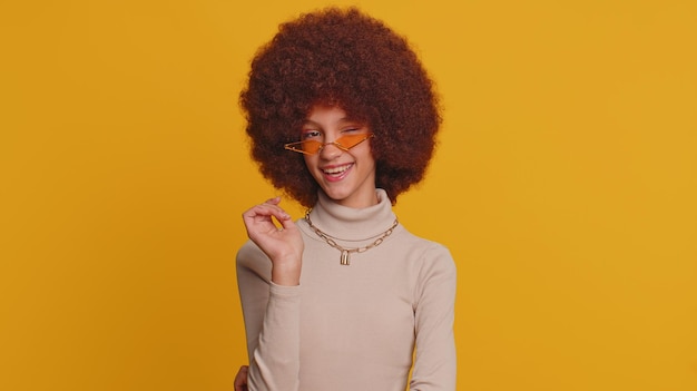 Portrait of young woman standing against yellow background