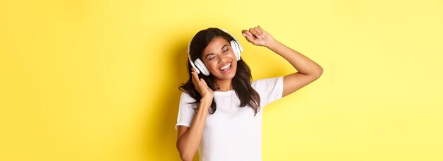 Photo portrait of young woman standing against yellow background