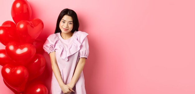 Portrait of young woman standing against yellow background