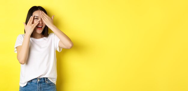 Portrait of young woman standing against yellow background