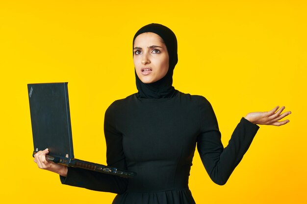 Portrait of young woman standing against yellow background