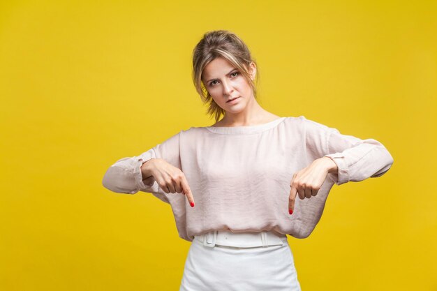 Portrait of young woman standing against yellow background