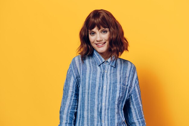 Portrait of young woman standing against yellow background