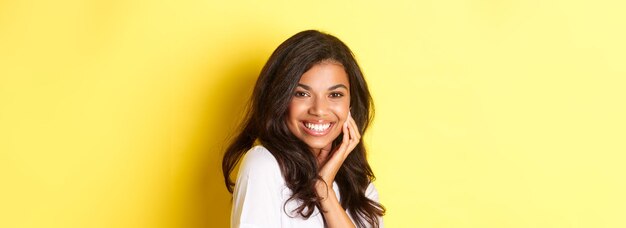 Foto ritratto di una giovane donna in piedi su uno sfondo giallo