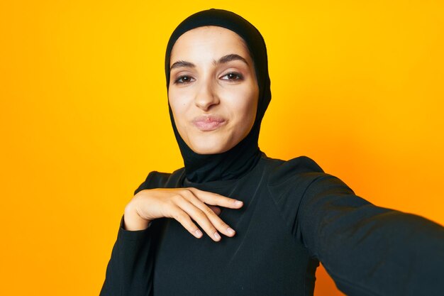 Portrait of young woman standing against yellow background