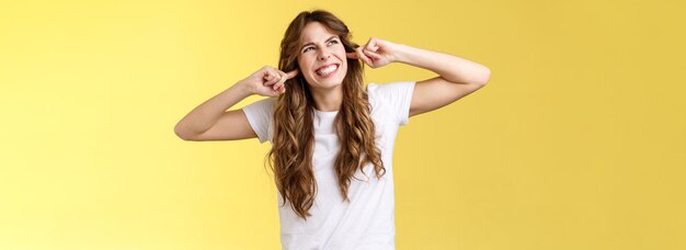 Portrait of young woman standing against yellow background