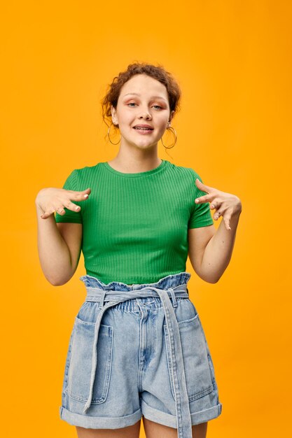 Portrait of young woman standing against yellow background