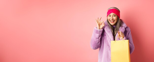 Portrait of young woman standing against yellow background