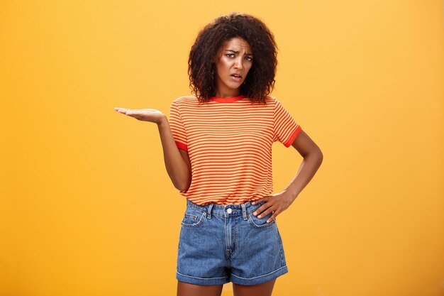 Portrait of young woman standing against yellow background