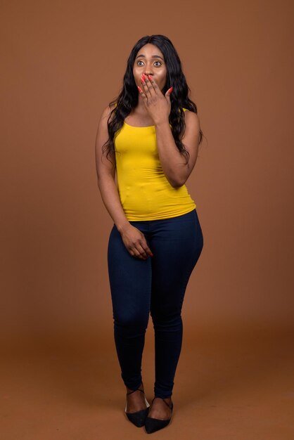 Portrait of young woman standing against yellow background