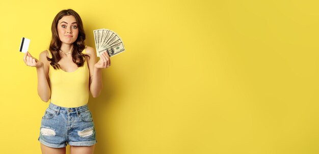 Portrait of young woman standing against yellow background