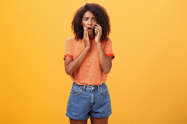 Portrait of young woman standing against yellow background