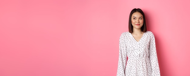 Portrait of young woman standing against yellow background