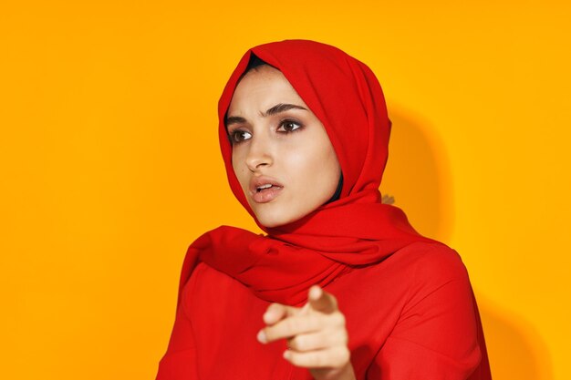 Portrait of young woman standing against yellow background