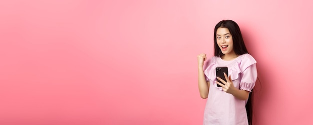 Portrait of young woman standing against yellow background