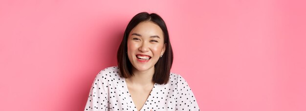 Portrait of young woman standing against yellow background