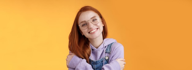 Portrait of young woman standing against yellow background