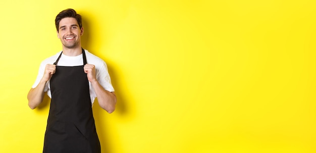 Portrait of young woman standing against yellow background