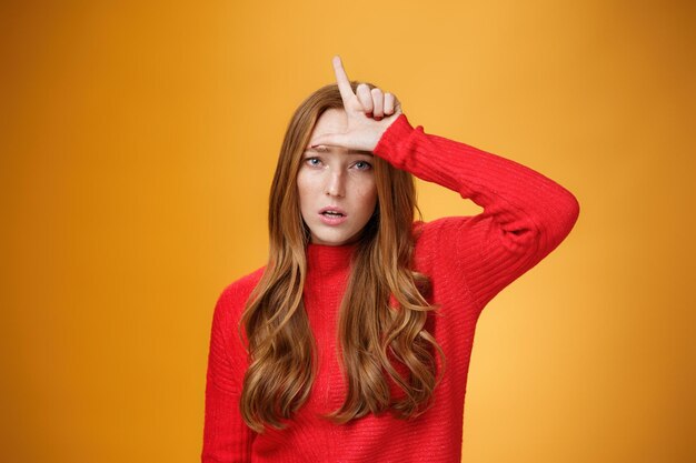 Portrait of young woman standing against yellow background