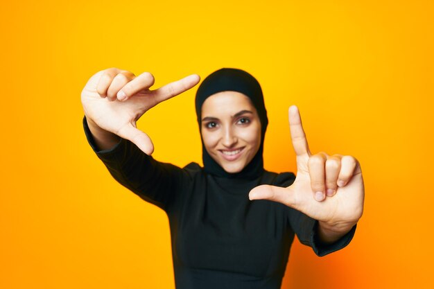 Portrait of young woman standing against yellow background