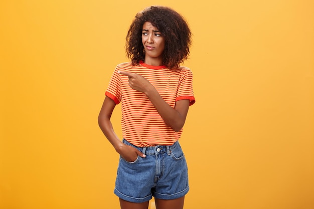 Portrait of young woman standing against yellow background