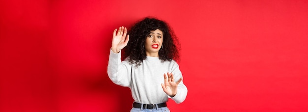 Portrait of young woman standing against yellow wall