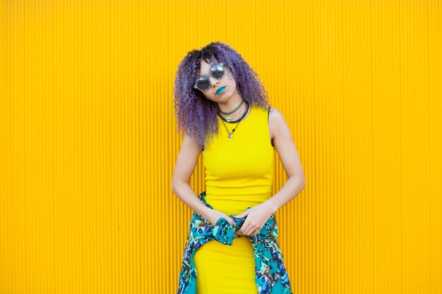 Portrait of young woman standing against yellow wall