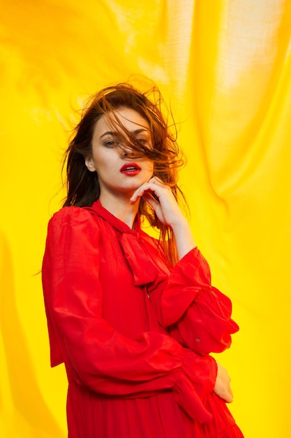 Portrait of young woman standing against yellow wall