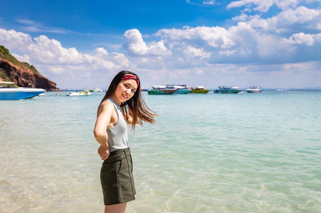 Portrait of young woman standing at beach against sky