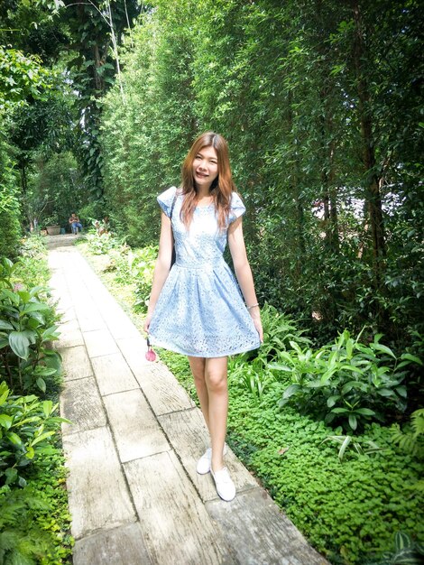 Portrait of young woman standing on boardwalk amidst plants