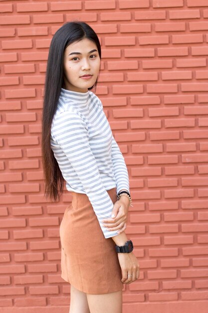 Photo portrait of young woman standing by brick wall