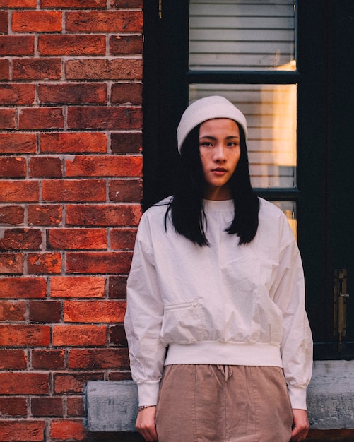 portrait of young woman standing by brick wall