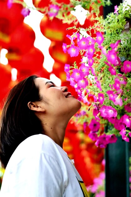 Foto ritratto di una giovane donna in piedi vicino a piante in fiore.