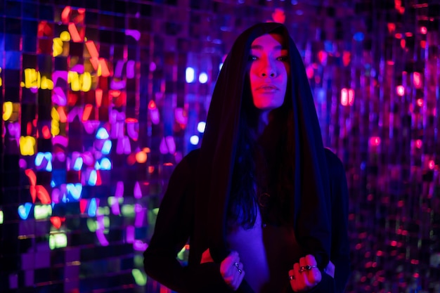 portrait of young woman standing by illuminated string lights