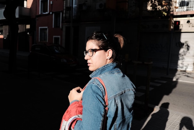 Portrait of young woman standing by street in city