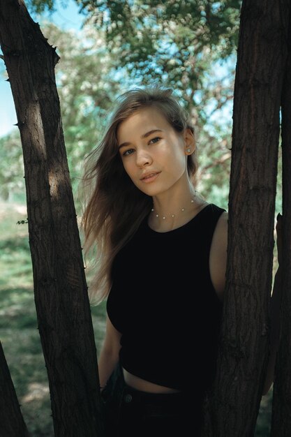 Portrait of young woman standing by tree trunk